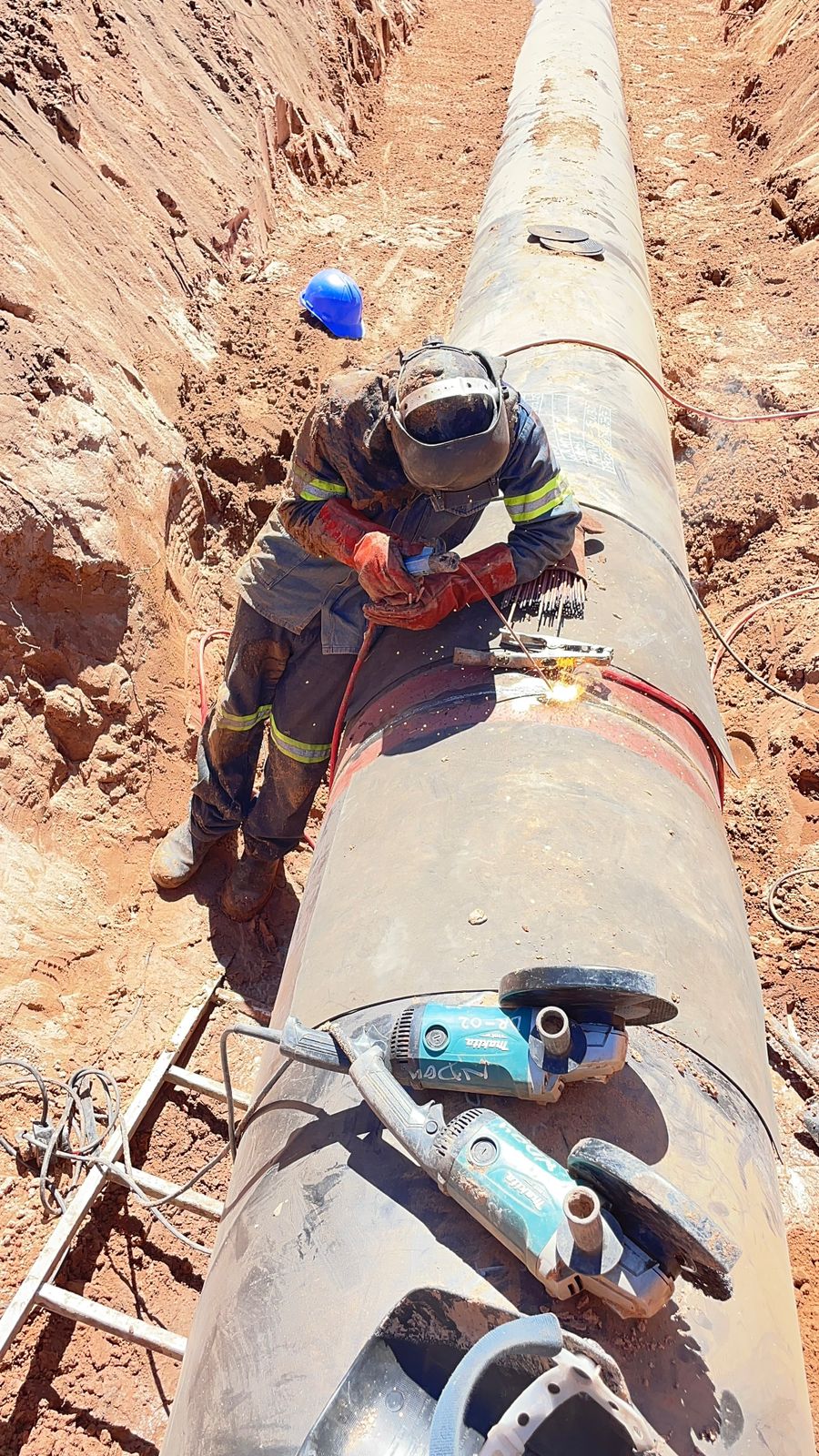 Welder joining large-diameter pipeline sections in an open trench