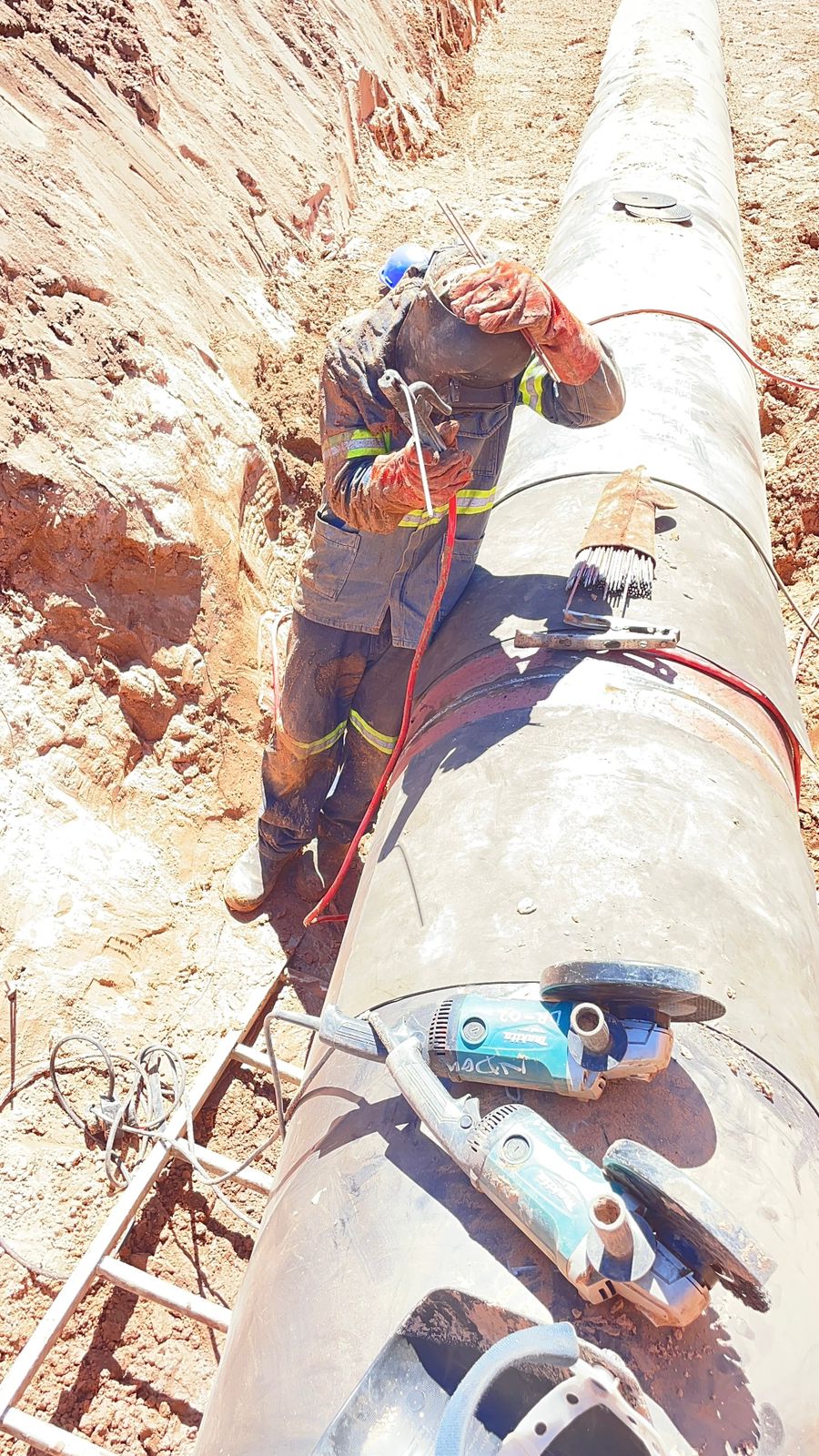 Pipeline welder preparing a large pipe joint in a trench